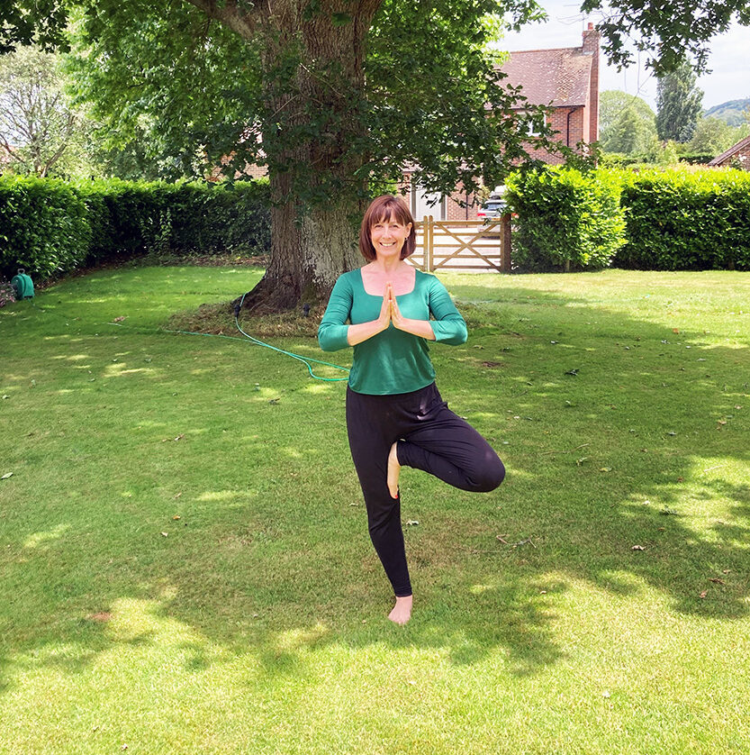 Jane in tree pose on a lawn under a large oak